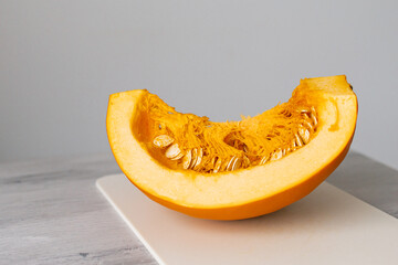 Cutted large raw Pumpkin Slice with seeds in orange flesh. Preparing seasonal vegetable for cooking vegetarian dish