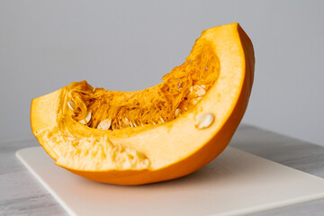 Cutted large raw Pumpkin Slice with seeds in orange flesh. Preparing seasonal vegetable for cooking vegetarian dish