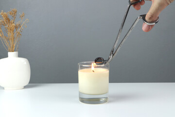 nice scented candle on the white table is cut the wick by silver stainless steel wick trimmer for...