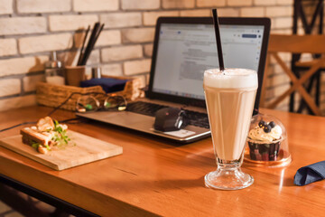 Close-up of table for coworking, remote work in cafe with laptop, coffee and quick meal.