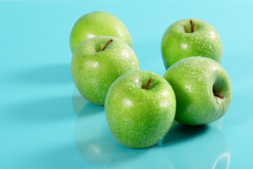 Close Up einer Gruppe von frischen, grünen Äpfeln ,auf cyanfarbigem Untergrund