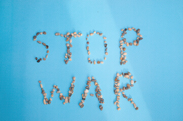 Stop war sentence made of stones on a blue background. Creative concept.
