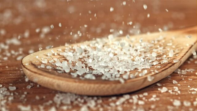 Sea salt crystals fall onto a wooden spoon. Filmed on a high-speed camera at 1000 fps. High quality FullHD footage