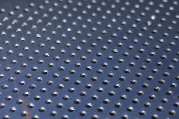 Steel plate with many circular holes drilled.