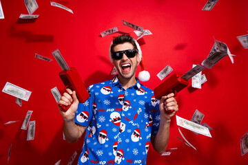 Photo of successful rich young guy shooting money gun usd bills businessman celebrating new year...