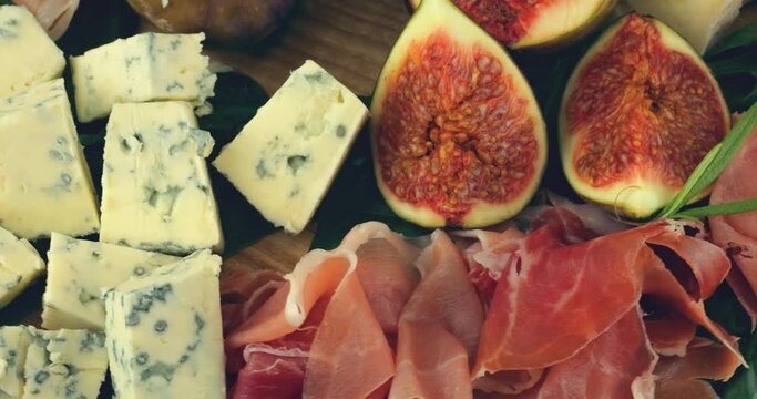 Figs, jamon, spinach leaves and blue cheeses on a wooden board. Snacks set.