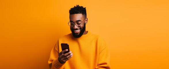 attractive african american man with phone against orange background. halloween,thanksgiving concept etc - obrazy, fototapety, plakaty