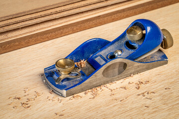 dusty hand block planer against  okoume plywood background with some shavings - woodworking concept - obrazy, fototapety, plakaty