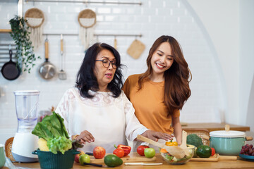 Asian lovely family in the kitchen. Beautiful female enjoy spending leisure time with senior elderly mom while cooking salad and food healthy