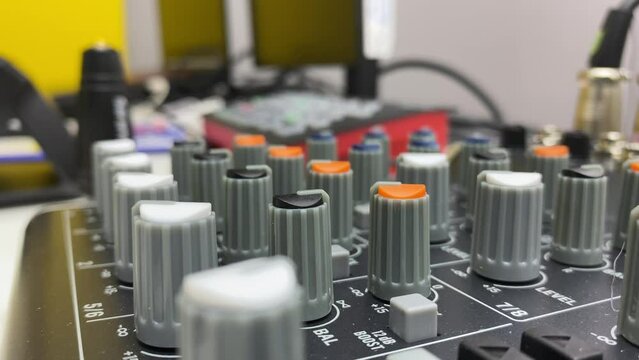 Audio equipment mixer console controller. Sound mixing tool on table inside studio point close up view. Technician hand turning dial switch.