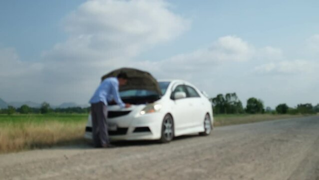 Blurred VDO image of businessman standing near broken car on country road. Car trouble. Emergency car stress.