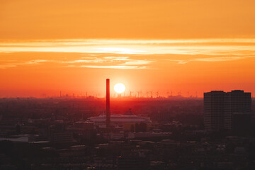 Sun setting over the horizon in Rotterdam. Red light irradiation of the wind farm and the harbour. Sunset in Netherlands