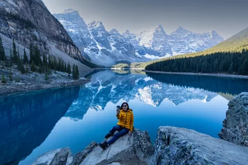 Papier Peint photo Gris female Asian backpacker travels and hikes to the top of a mountain and tourists take smartphone selfies with the view of Moraine lake in Banff National park.