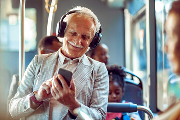 Happy elderly businessman using a smartphone on the bus