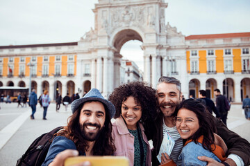 Young and diverse group of friends taking selfies in front of the Rua Augusta Arch while on vacation in Lisbon