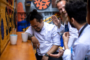 Young male chefs laughing after work in the restaurant