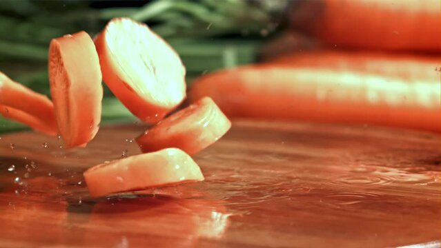 Pieces of chopped carrots fall onto a wet board. Filmed on a high-speed camera at 1000 fps. High quality FullHD footage