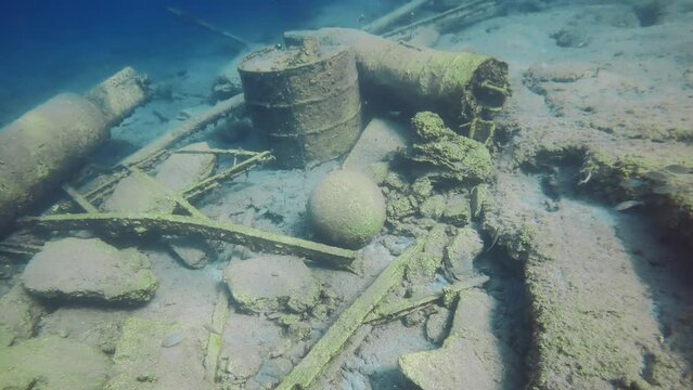 Close-up, Old stone cannonball lying on rocky seabed next to destroyed pier in Mediterranean Sea, Greece, Camera moving forwards approaching the cannon ball