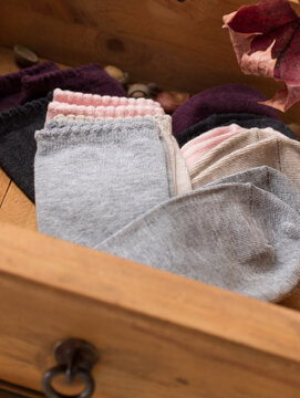 farbige Socken in Pastellt&ouml;nen, herbstlich arrangiert in einer Holzschublade, in warmer Stimmung ,als Close Up