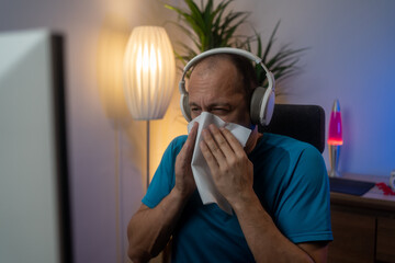 Sick, allergy and blowing nose with man in home office for flu illness, hay fever and sneeze. Allergies, virus and sinus with employee and sneezing with tissue for influenza, cold and healthcare