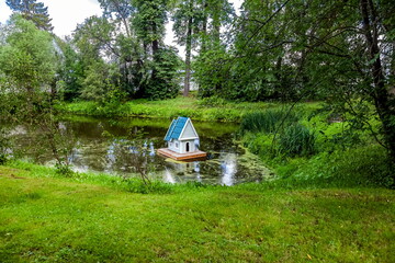 Wooden house for swans on a small artificial lake in summer