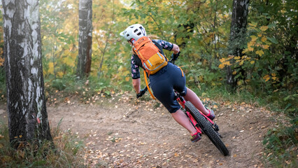 Bike downhill on single trails. A girl cyclist with his bike riding banked turn.