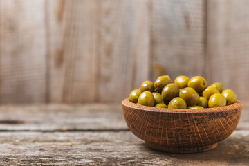 Green olives on  background. Various types of olives in bowls and fresh olive leaves. Vegan. Olive fruits. Place for text. Copy space.