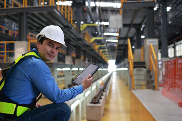 Portrait Young railway engineer with safety vest and hard hat using tablet to check the railway system