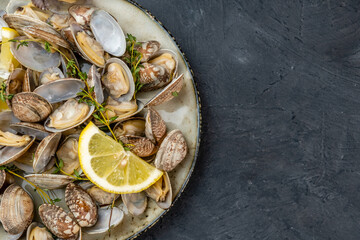 Healthy food, vongole clams cooked with herbs and lemon, top view. Dark background. Free space.