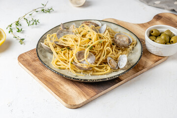 Pasta with seafood, vongole and parmesan, on a light table, serving board.
