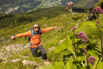Top view of gray-haired long-haired male traveler with backpack among alpine slopes, Austria