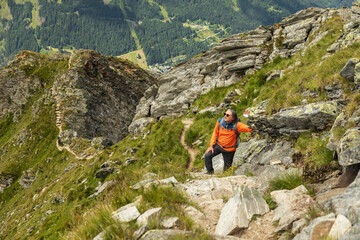 Man stopped on climb on rocky trail and resting on rocky ridge background, Austria
