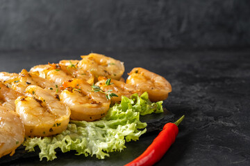 Grilled shrimp peeled in oil, close-up, dark background.
