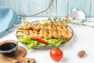Appetizing shrimp skewers in a plate, light table. Served with lettuce and lemon