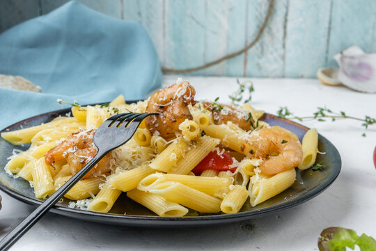 Homemade pene pasta with shrimp, homemade food, parmesan with pasta, fork with shrimp, selective focus.
