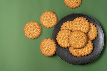 Composition of French cookies on a black plate and on a green background. View from above. Food Flat Lay.