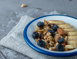 Muesli with blueberries, almonds, banana and blueberries in an iron white plate on a linen napkin. Morning breakfast. Healthy eating concept.
