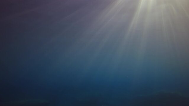 View from underwater of sun light at sunrise with ripples on waves surface. Light from the morning sun filters down through water in sundown