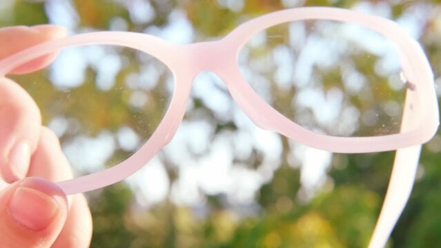 glasses with dirty lenses in female hands, individuals with poor vision adapt lifestyle choices and habits accommodate visual needs, Eyeglass Fashion