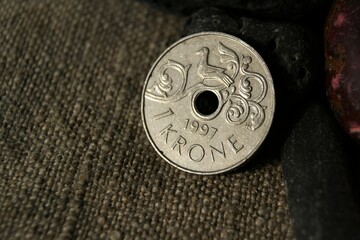 1 Krone Harald V. Norwegian coin and stones on natural linen fabric. Business and finance.