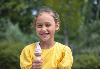 Cute laughing child little girl eats ice cream on a hot day. Ice cream in a waffle cone. A happy...