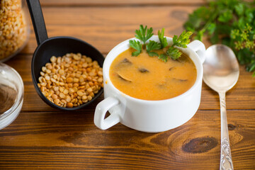 Cooked dried pea puree soup with mushrooms in a bowl .