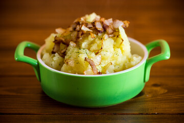 Cooked mashed potatoes with fried chopped bacon and onions.