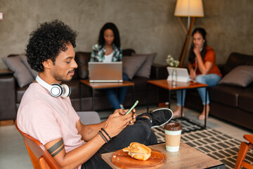 black university student using mobile and having snack in coffee shop