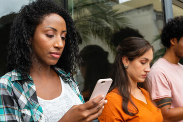 serious woman looking at mobile screen with friends standing