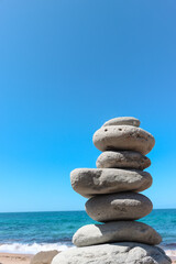 Zen stone little pile on sea beach. The stones of the pyramid balance on the rock. Zen stones balance spa on beach.