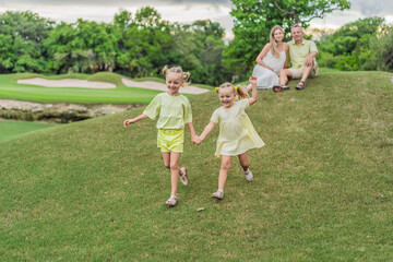 Fototapeta premium A happy family, two girls, dad, and a pregnant mom, enjoys quality time together on a lush green lawn, creating cherished memories of togetherness