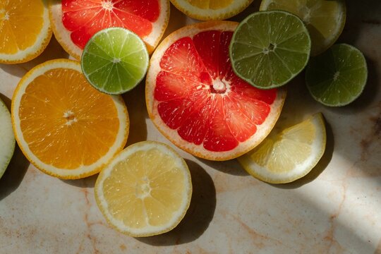 Selection of citrus fruits, freshly cut and arranged in a decorative pattern on a white serving tray