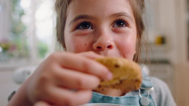 Face, girl and eating cookie in kitchen, happy and enjoy break. Young female, child and delicious biscuit for lunch, chewing tasty treat and snack for fun, portrait and happiness at home on vacation.