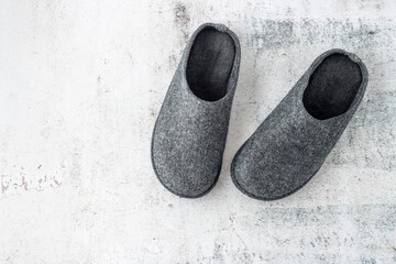 Dark grey felt wool home male winter pair slippers on stone floor background